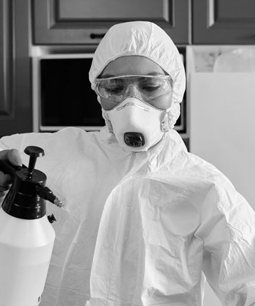 Worker in protective suit spraying disinfectant